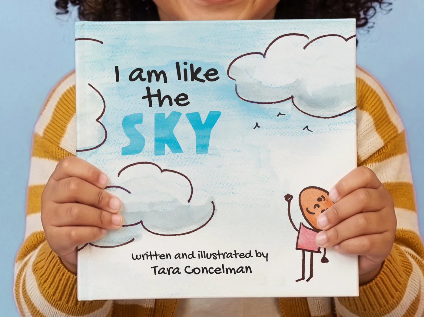 A child holding a copy of I Am Like The Sky